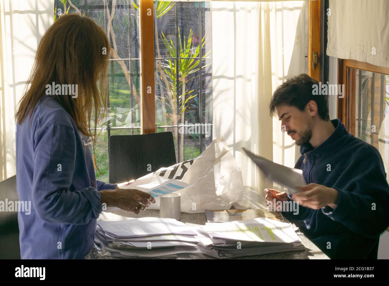Giovane adulto uomo e donna adulta revisione della documentazione cartacea in ambiente luminoso Foto Stock