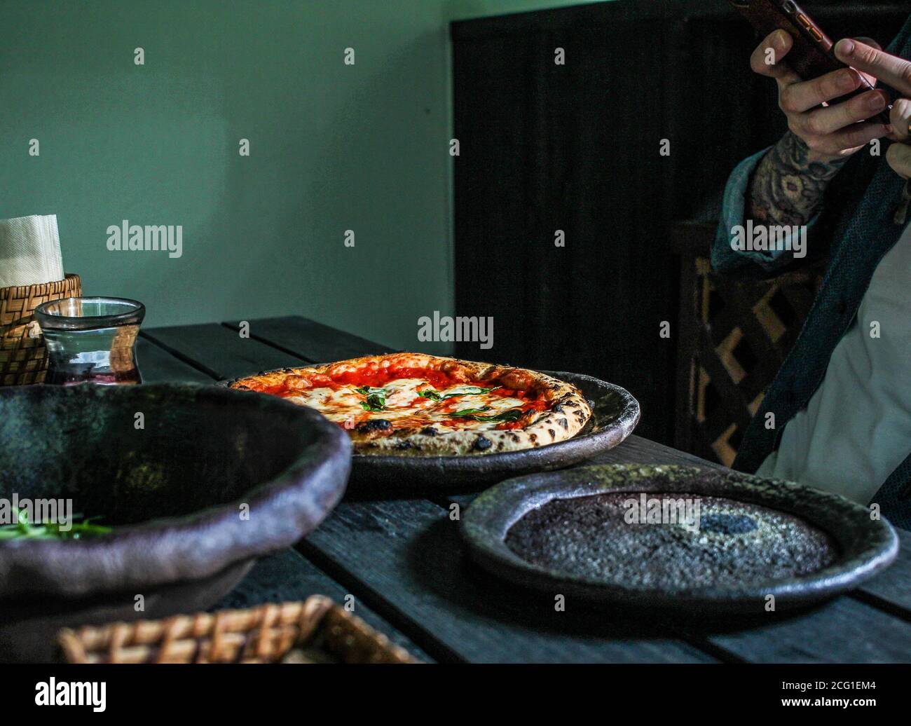 Uomo che scatta una foto di una pizza cotta a legna ad un ristorante Foto Stock