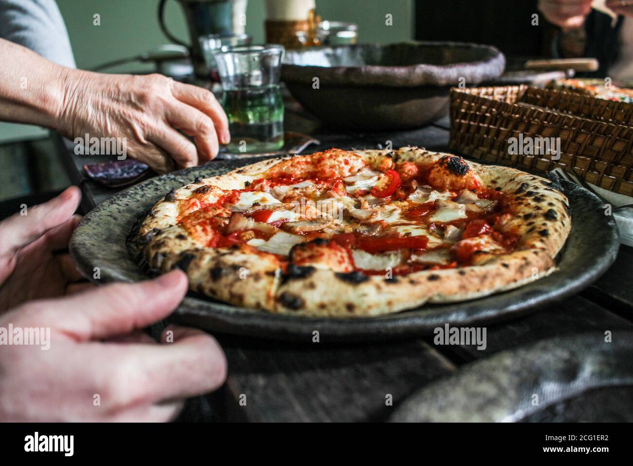 Persona che serve pizza cotta a legna in un ristorante in Giappone Foto Stock