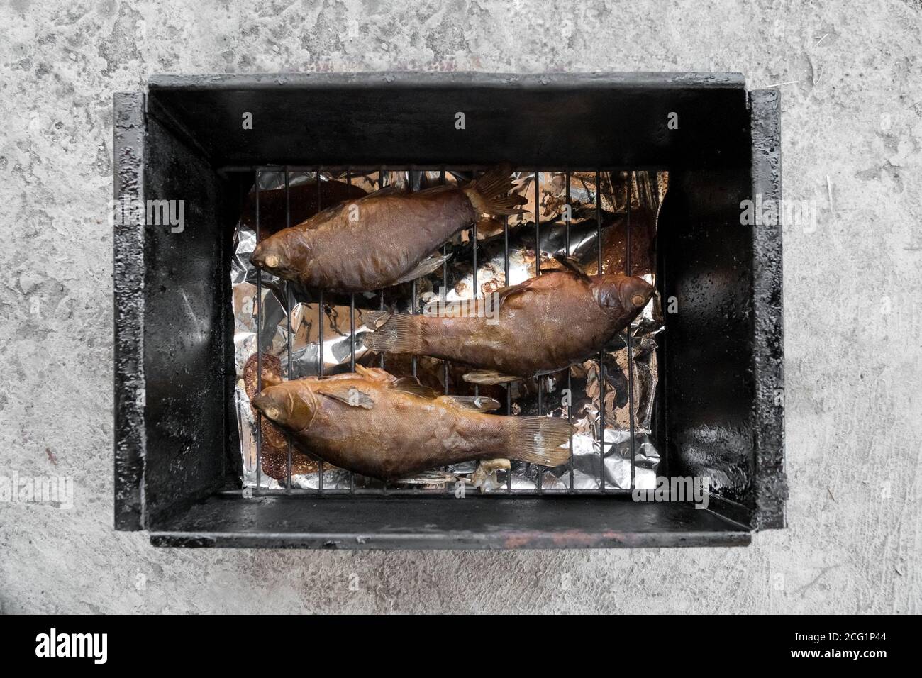 Crogiolo di pesce affumicato di fiume giace su una griglia di filo in una casa fumatore. Foto Stock