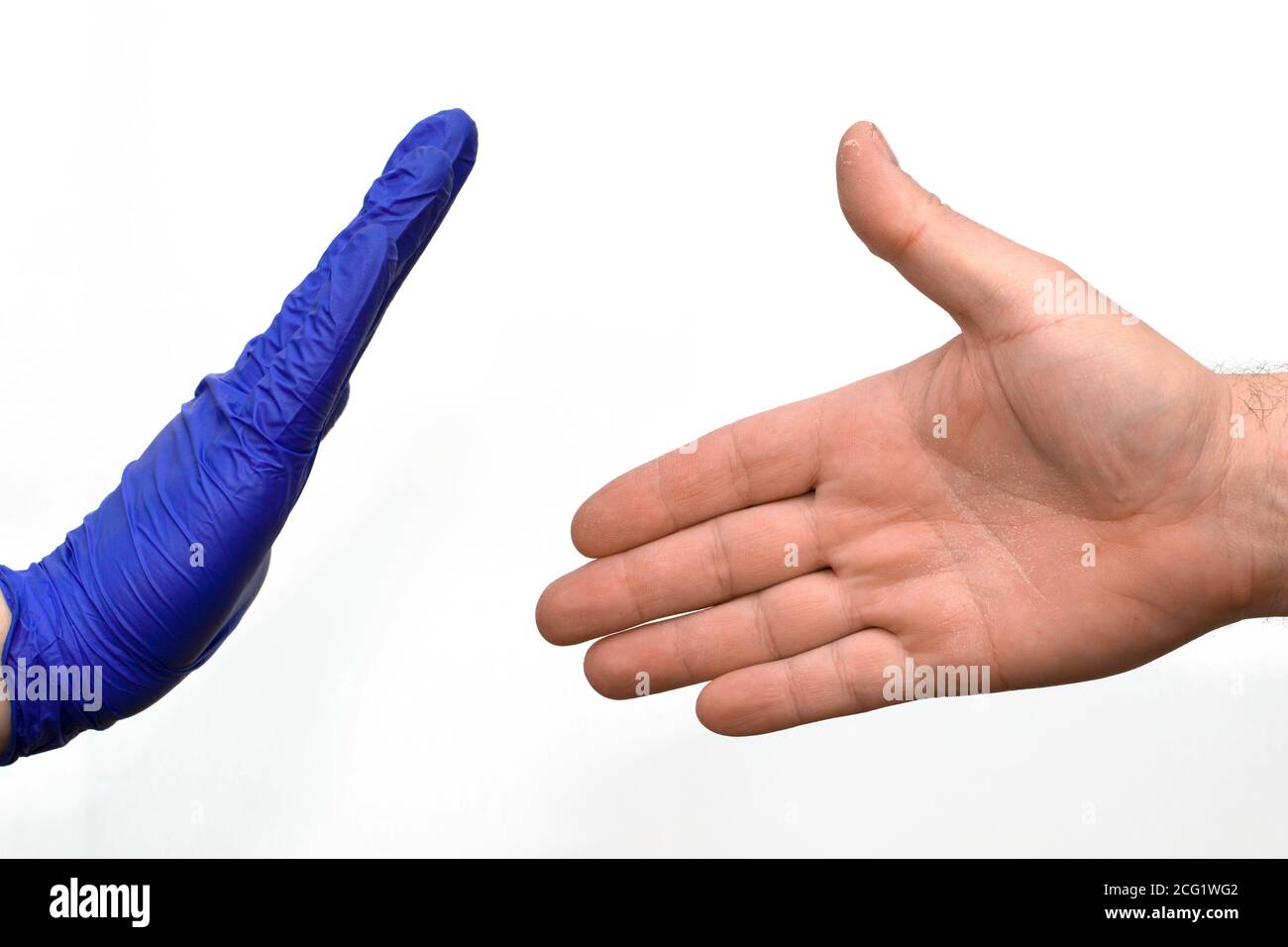 un cazzo di un uomo in un guanto medico blu blocca una mano non protetta cercando di salutarlo Foto Stock