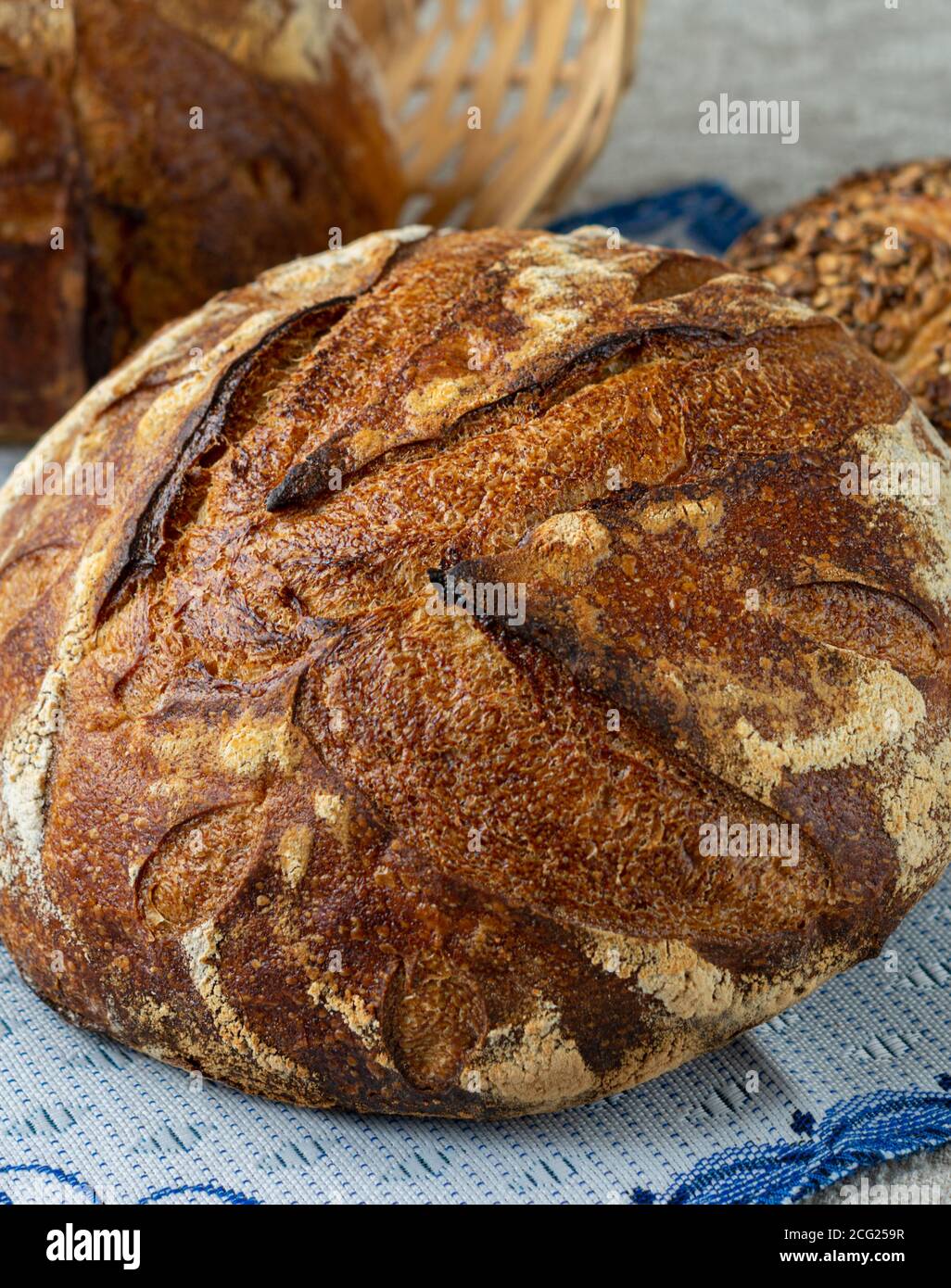 Primo piano di un pane artigianale su un tovagliolo di stoffa blu. Pane fatto in casa con semi di pasta di origine Foto Stock