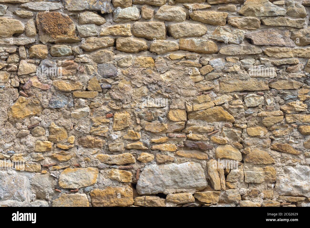 Mattoni gialli invecchiati e pietre sfondo muro. Struttura superficiale di muratura. Architettura orizzontale della tecnologia della muratura in mattoni. Chiudi muro di mattoni Foto Stock