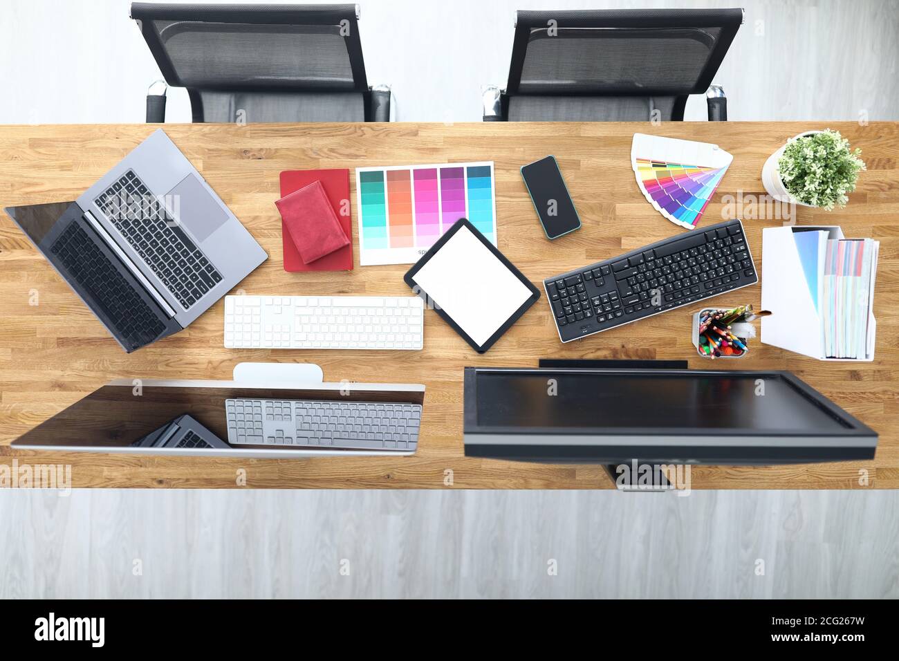 Luoghi di lavoro in sedie da tavolo da ufficio tavoletta smartphone tavolozza colori matite tablet tastiera monitor. Foto Stock