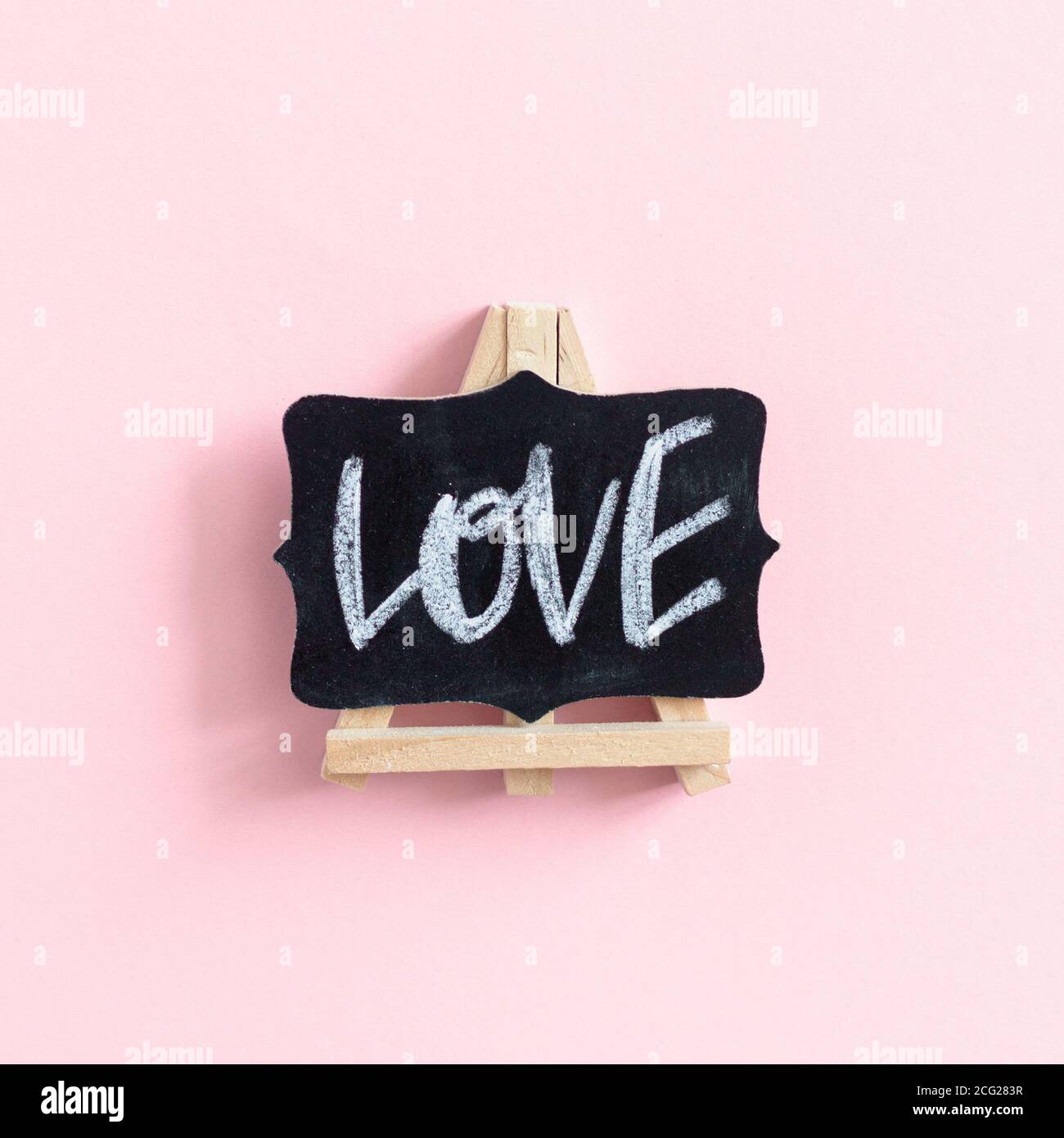 Parola Amore scritto a mano su una lavagna su un pastello rosa sfondo Foto Stock