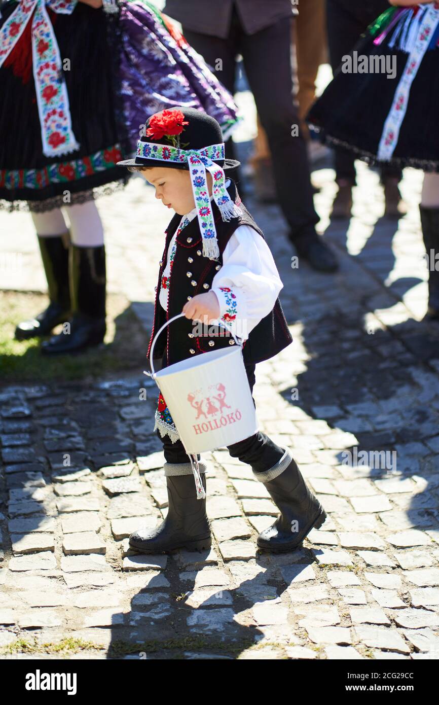 Ragazzo vestito in un costume tradizionale folk che porta un secchio nel villaggio di Holloko, paese ungherese Foto Stock