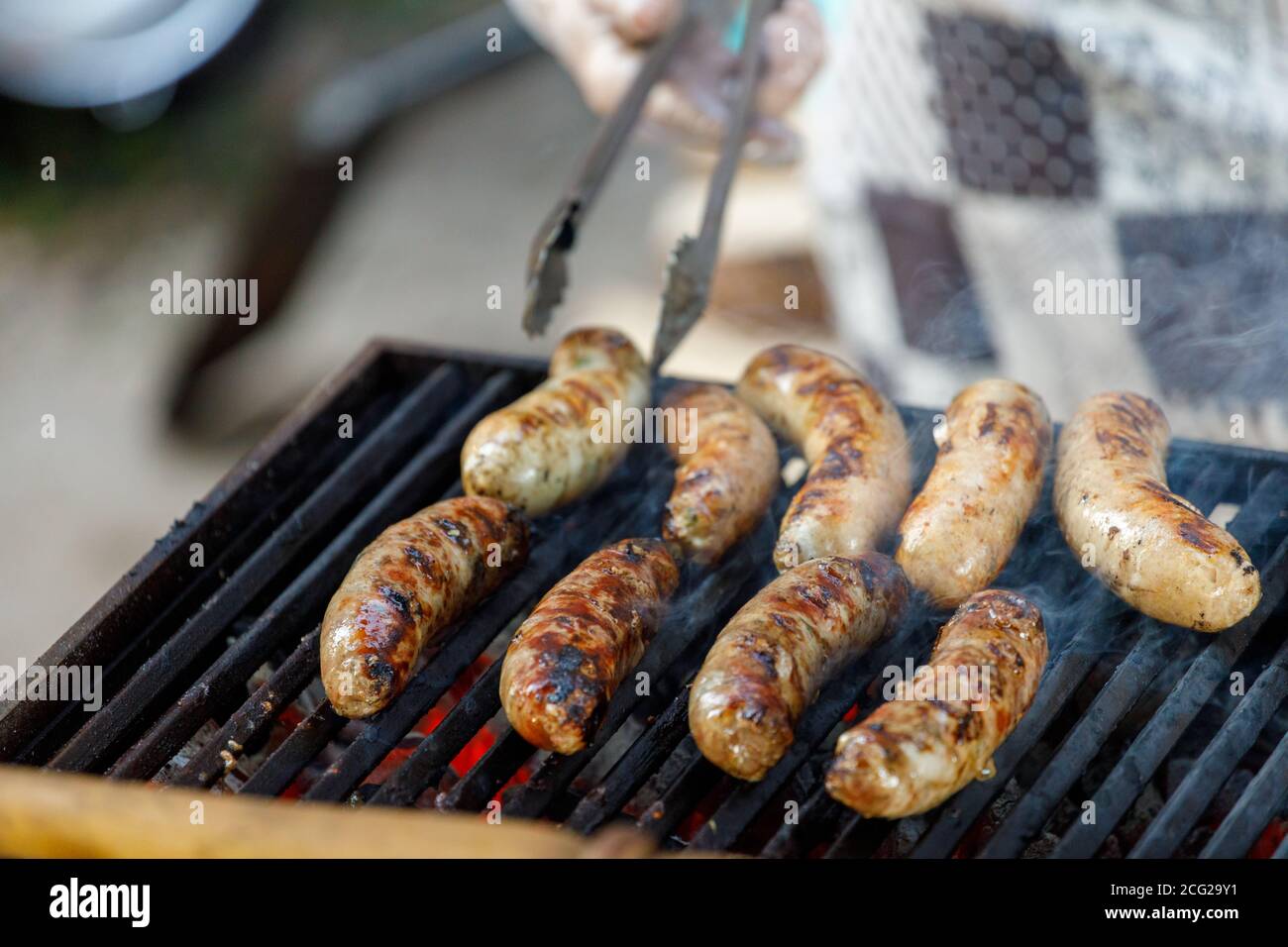 l'uomo patisce salsicce su griglia. picnic estivo Foto Stock