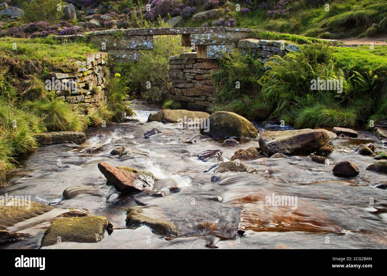 Le acque del South Dean Beck che scorrono sotto un ponte di pietra, su Haworth Moor, nel paese di Bronte, nello Yorkshire, Regno Unito Foto Stock
