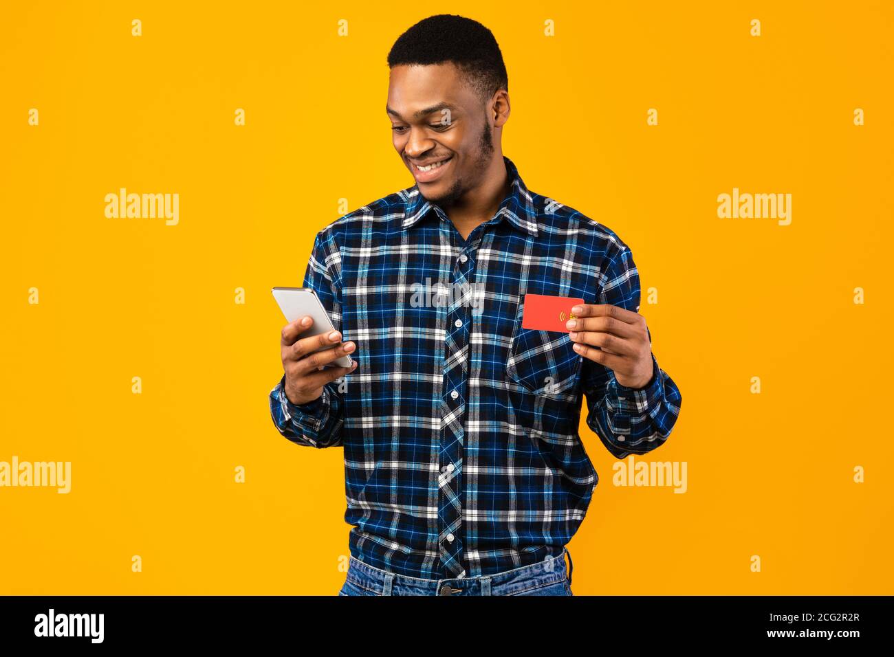 Happy Black Man con smartphone che tiene la carta di credito in Studio Foto Stock