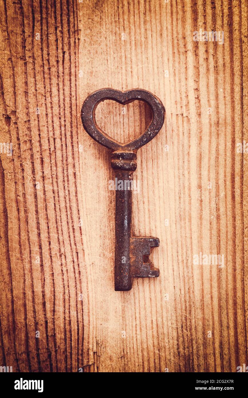 Vecchio arrugginito chiave vintage a forma di cuore, uno sfondo di legno. Amore e il giorno di San Valentino biglietto di auguri Foto Stock