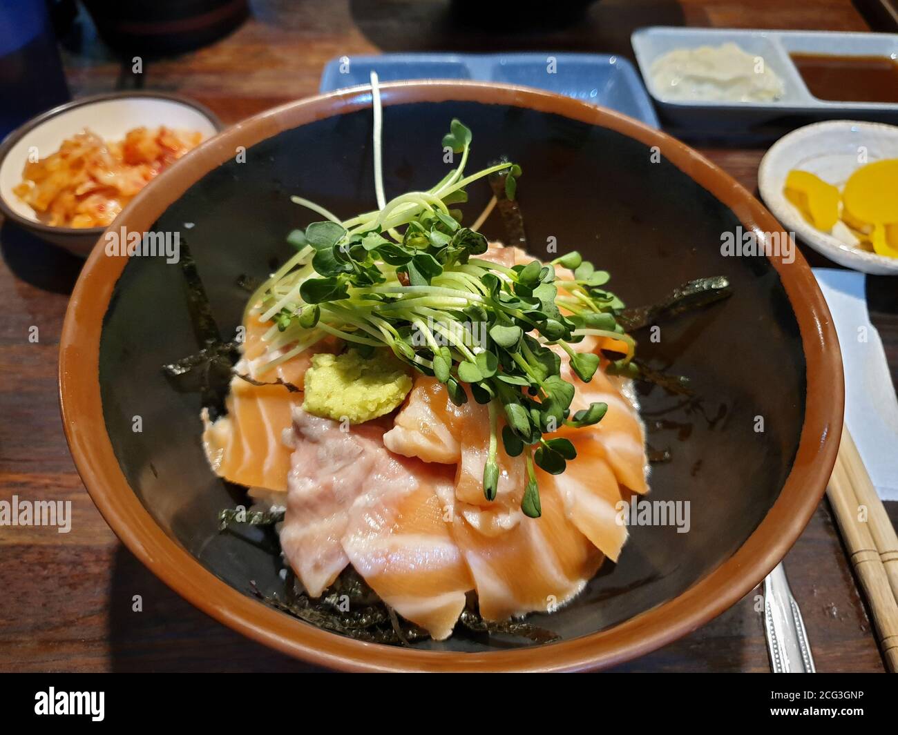 Sake-don, o Donburi al salmone, piatto tradizionale giapponese di riso con farine di pancia di salmone crudo, wasabi e germogli. Condito con salsa di soia. Foto Stock