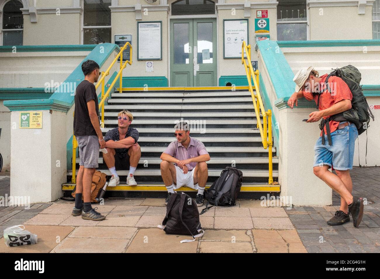 GIOVANI UOMINI CHE ASPETTANO FUORI DALLA STAZIONE FERROVIARIA DI LONDRA ROAD, BRIGHTON, REGNO UNITO Foto Stock