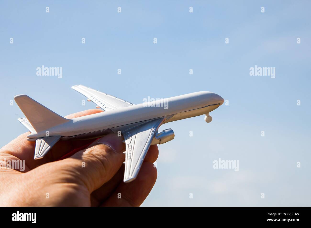 Mano con il giocattolo dell'aeroplano contro il cielo blu Foto Stock