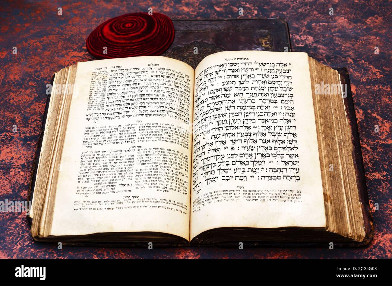 Bibbia ebraica. Un vecchio libro ebraico aperto e una balla ebrea a maglia rossa. Torah in ebraico e aramaico con i commenti di Rashi e o ha-haim. Primo piano Foto Stock
