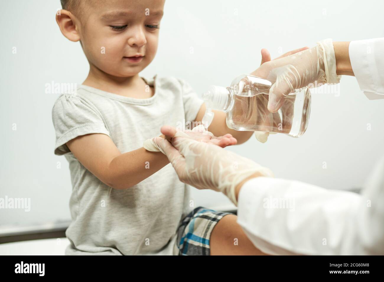 Medico che mette l'igienizzatore per le mani del bambino. Insegnare ad un  bambino il lavaggio delle mani e l'igiene. Esame fisico del bambino di 1  anno. Bene-bambino Foto stock - Alamy