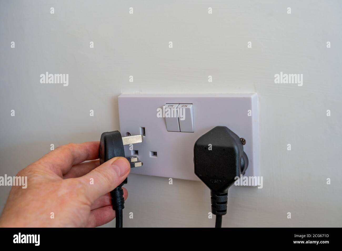 Collegamento Focus selezionato in un Regno Unito (inglese) connettore maschio con fusibile a tre pin in una presa a muro doppia per il collegamento un'apparecchiatura per l'alimentazione elettrica a 240 v. Foto Stock
