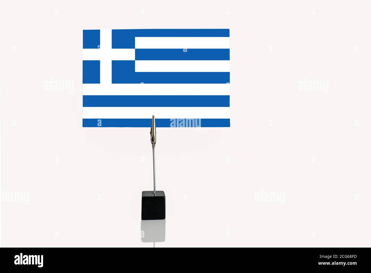 Bandiera in miniatura della Repubblica ellenica di Grecia a base cubica in supporto per foto su sfondo bianco Foto Stock