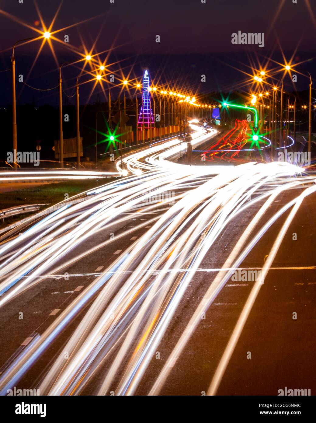 Tracce di fari da auto che si muovono di notte sul ponte, illuminati da lanterne. Paesaggio astratto della città con autostrada. Foto Stock