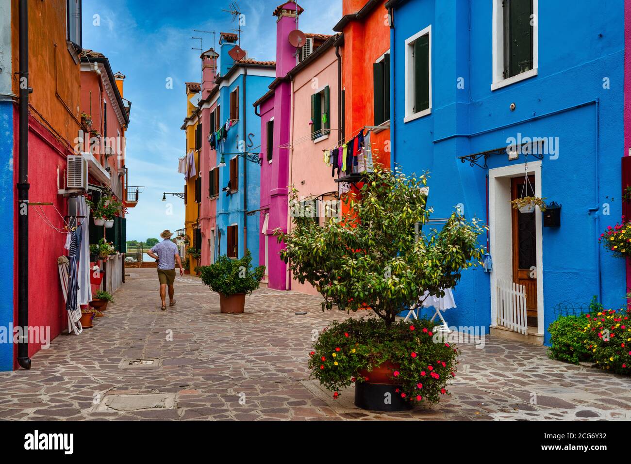 Uomo a piedi attraverso case multicolore, Burano, Venezia, Veneto, Italia Foto Stock