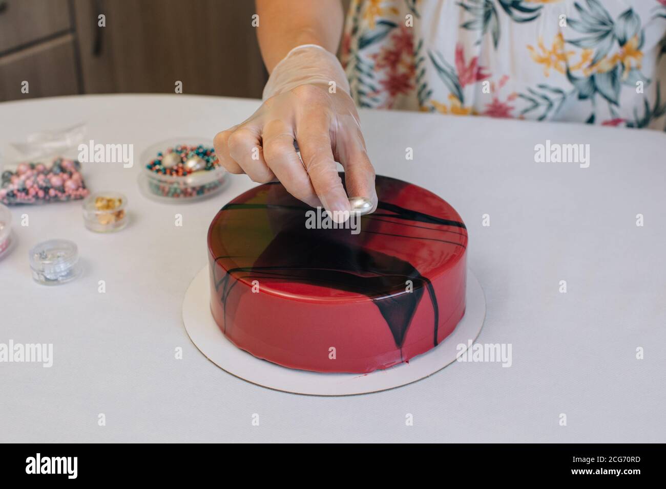 Donna che decora una torta di cioccolato di velluto rosso di cioccolato fatta in casa Foto Stock