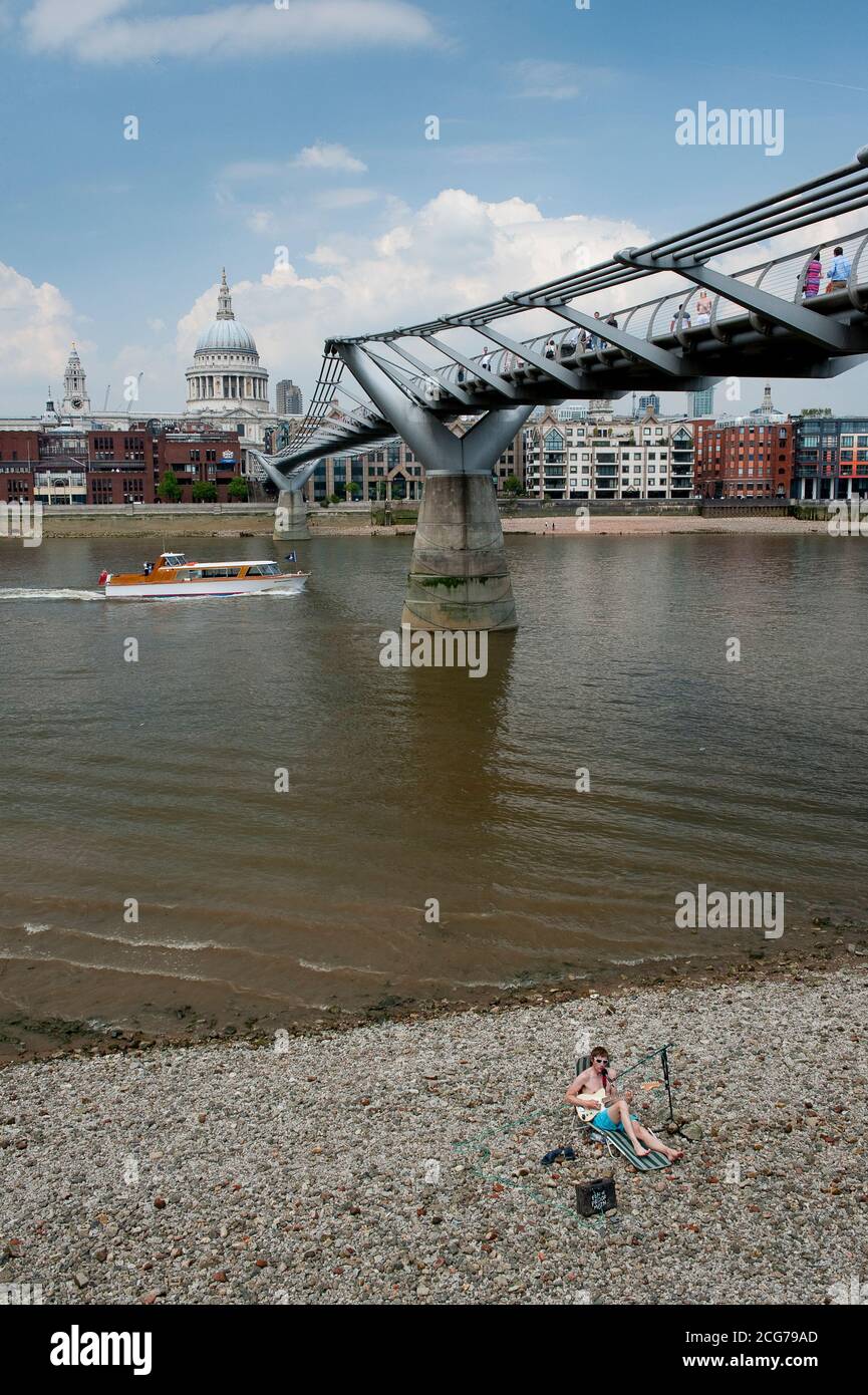 Busker di fronte al Millennium Bridge che attraversa il Tamigi con la Cattedrale di St Paul sullo sfondo, City of London, Inghilterra. Foto Stock