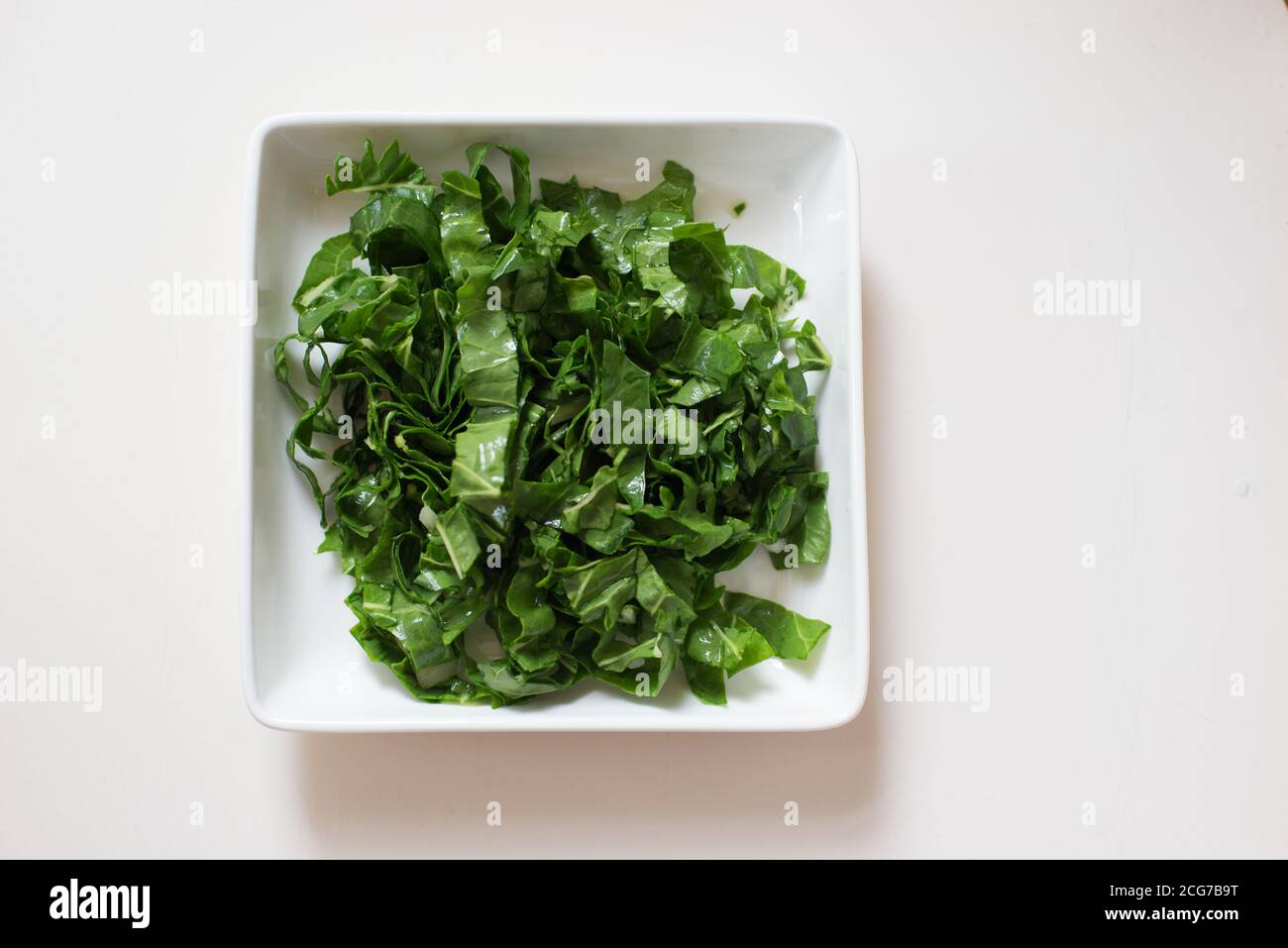 Spinaci tritati in un piatto bianco Foto Stock