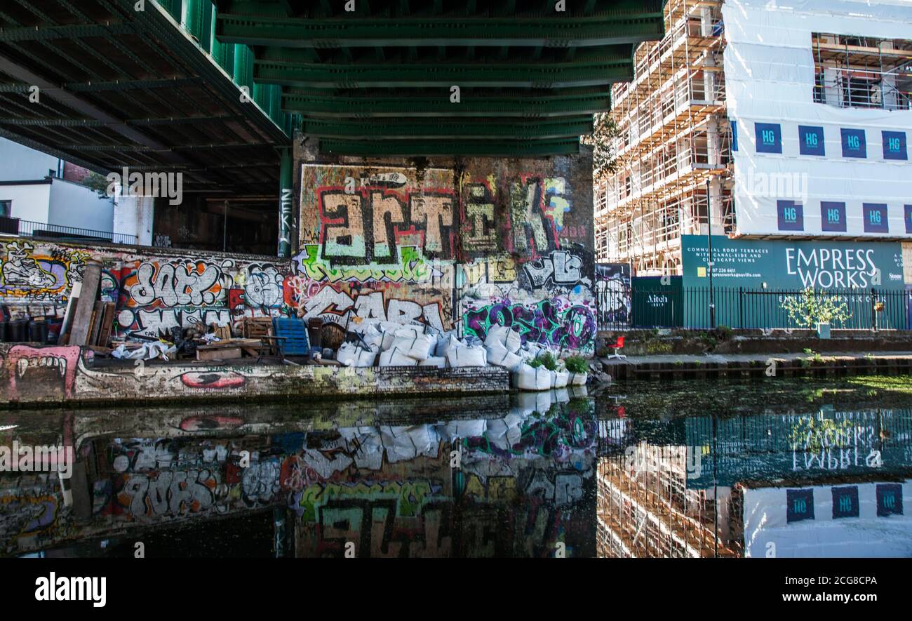 Regents Canal a Londra, Inghilterra, Regno Unito con le opere d'arte sulle pareti riflesso nell'acqua sotto il ponte Foto Stock