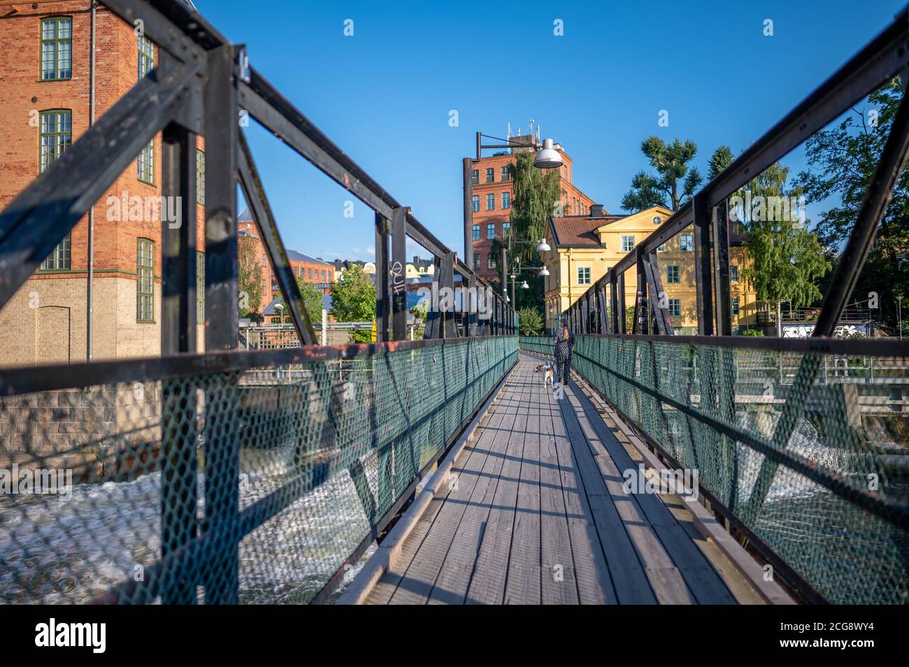 Footbride attraverso il fiume Motala nel vecchio paesaggio industriale durante l'estate in Norrkoping. Norrkoping è una storica città industriale svedese. Foto Stock