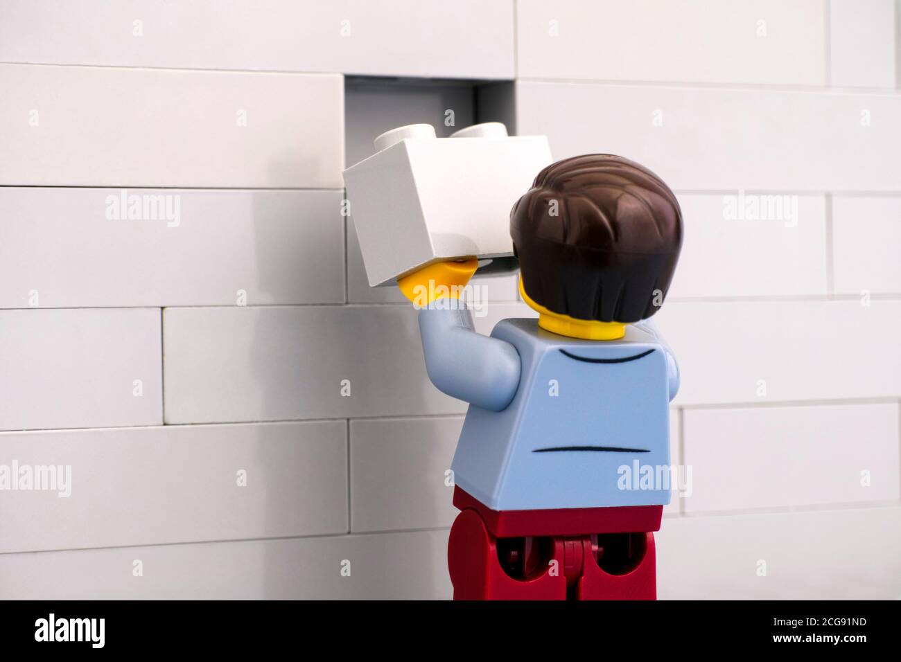 Tambov, Federazione Russa - 07 Giugno 2020 minififigura Lego man con mattone grigio che rifiniscono un muro Foto Stock