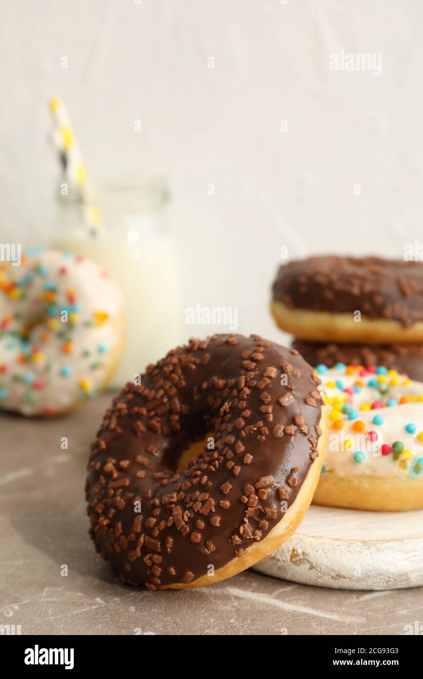 Vasetto di latte e gustose ciambelle sul tavolo grigio Foto Stock