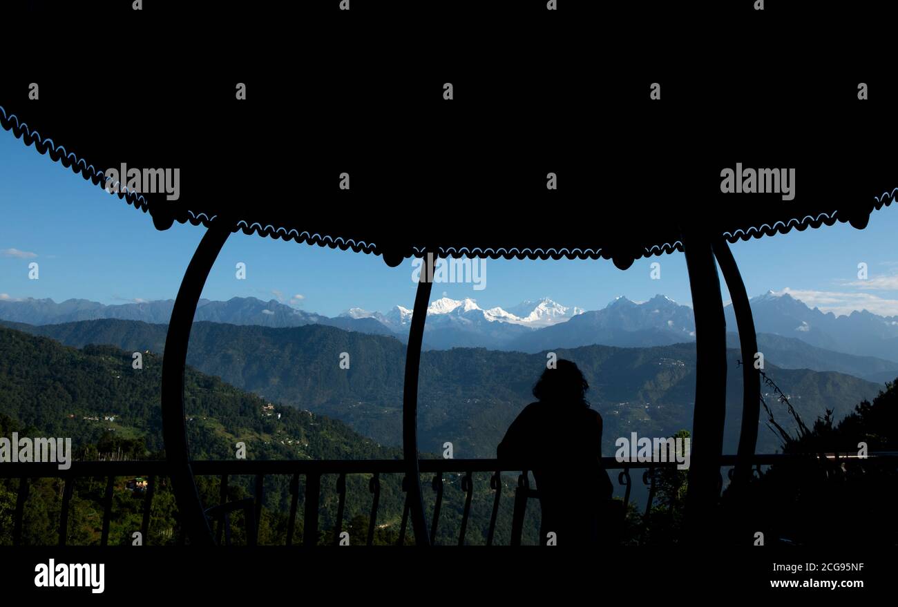 Il possente Kanchanjunga con altre cime innevate sullo sfondo di un piccolo villaggio sul pendio delle montagne sopra L'Himalaya dal balcone di un tou Foto Stock