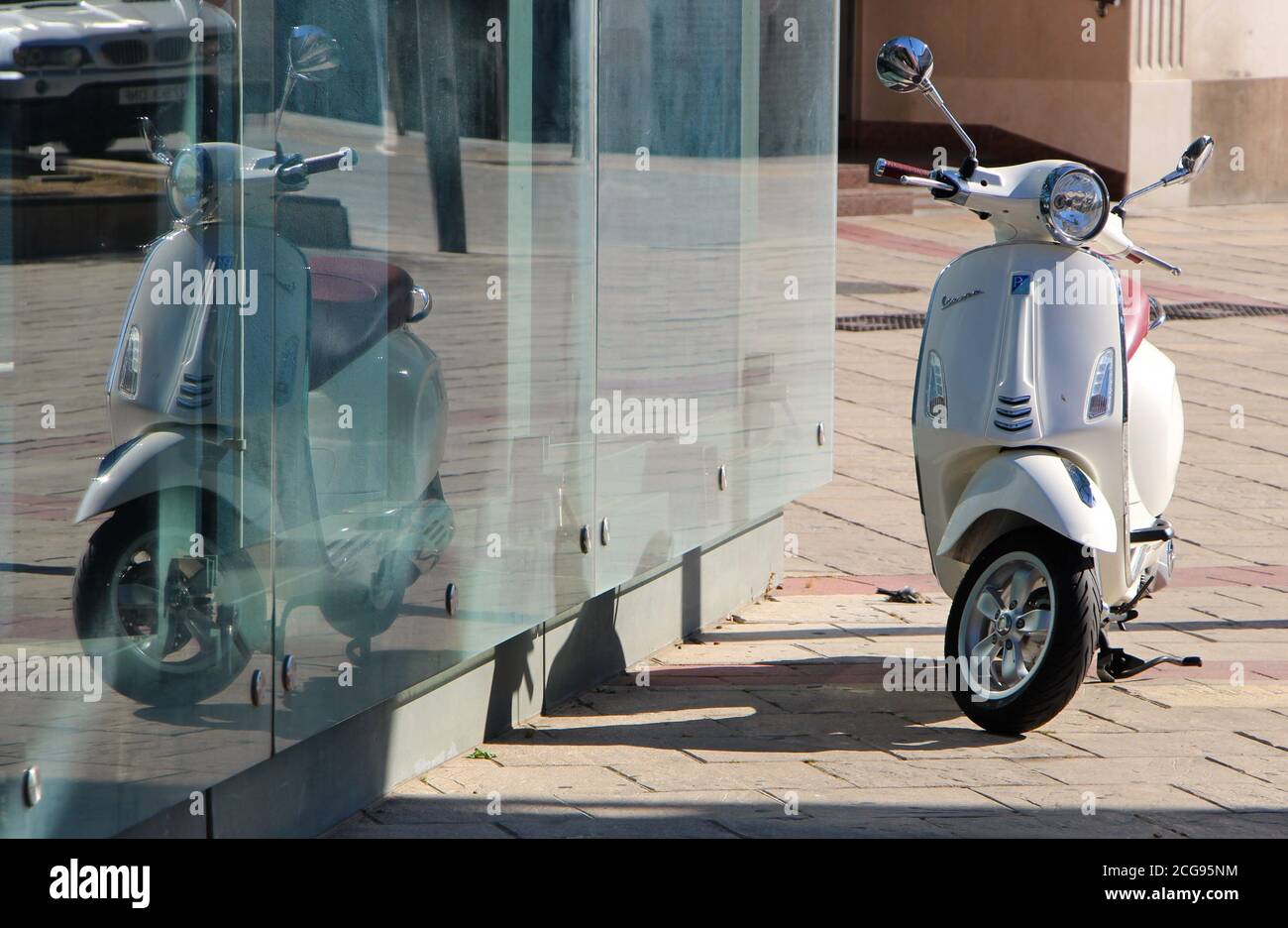 2019 Piaggio Vespa 125cc Primavera parcheggiato su un terreno pavimentato riflesso in vetro con un uccello morto a terra In estate sole Palencia Castiglia e Leon Foto Stock