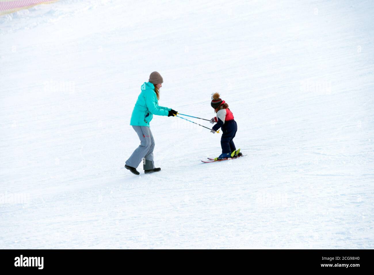 Mamma insegna alla figlia di sciare sulla montagna. Foto Stock