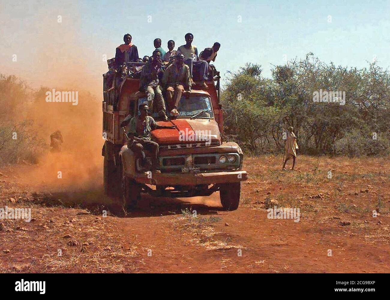 1993 - dritto sulla ripresa di una fine del modello di motore Isuzu camion caricati con gli uomini somali. Un uomo corre sul parafango anteriore destro mentre due altri giro sulla parte superiore del carrello della cabina di guida. Essi sono dal villaggio di Maleel e sono in arrivo alla zona di atterraggio dove sacchi di grano vengono consegnate (non mostrato). Questa missione è a diretto sostegno di Restore Hope. Foto Stock