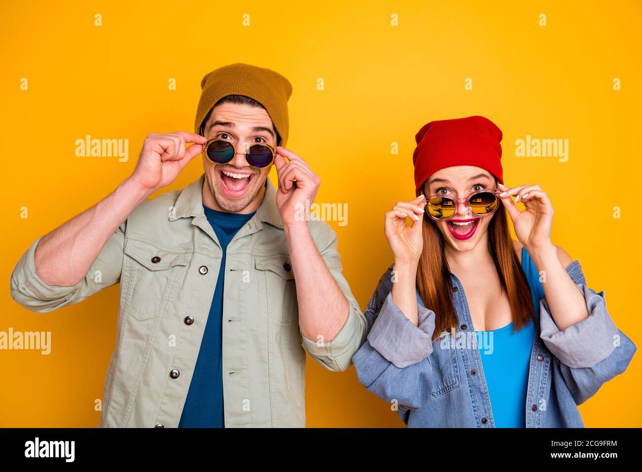 Foto di due simpatiche e positive persone sbalordite che decollo occhiali isolati sfondo giallo estivo Foto Stock