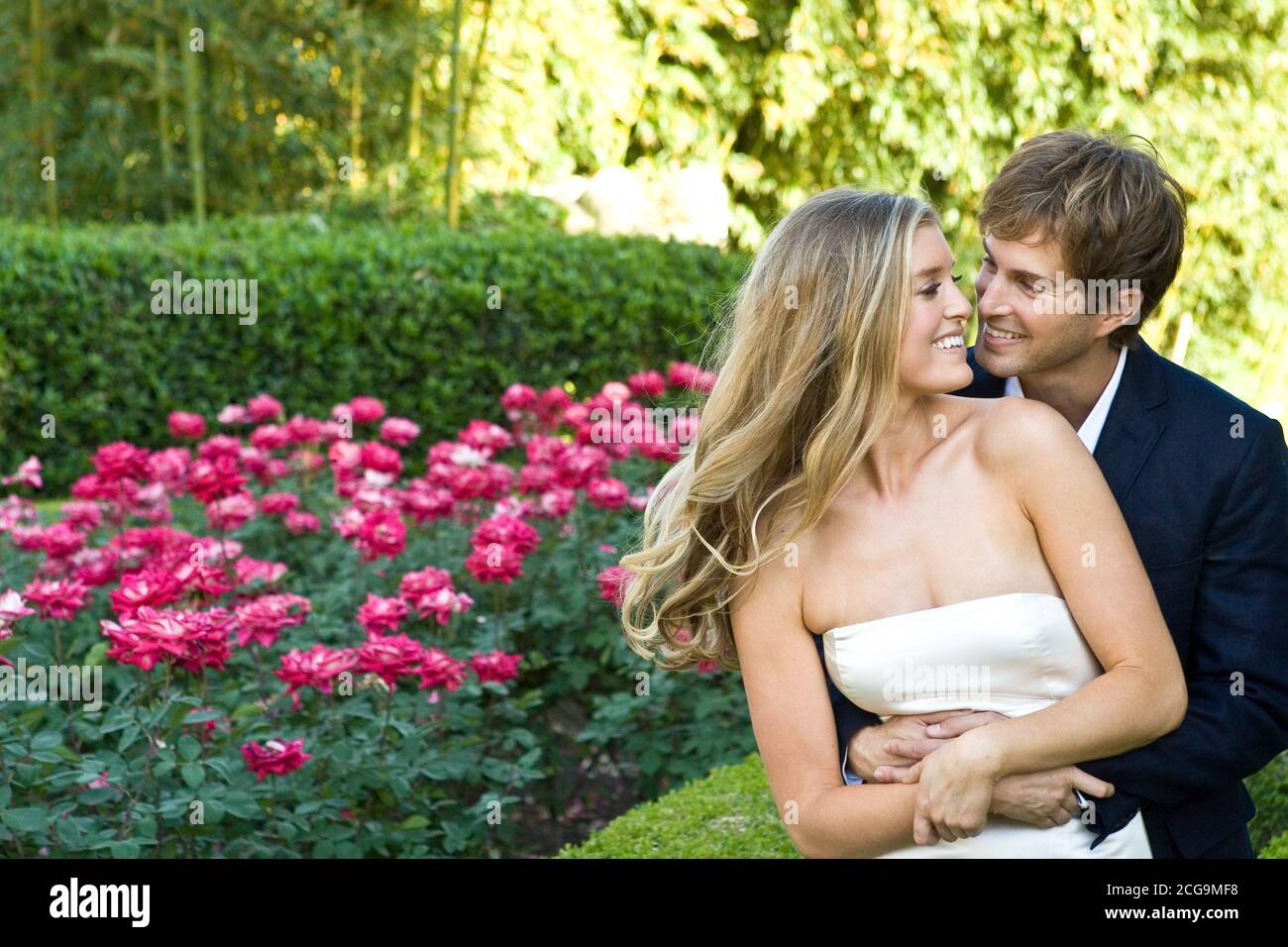 Una bella giovane coppia si abbracca fuori in un giardino. Foto Stock