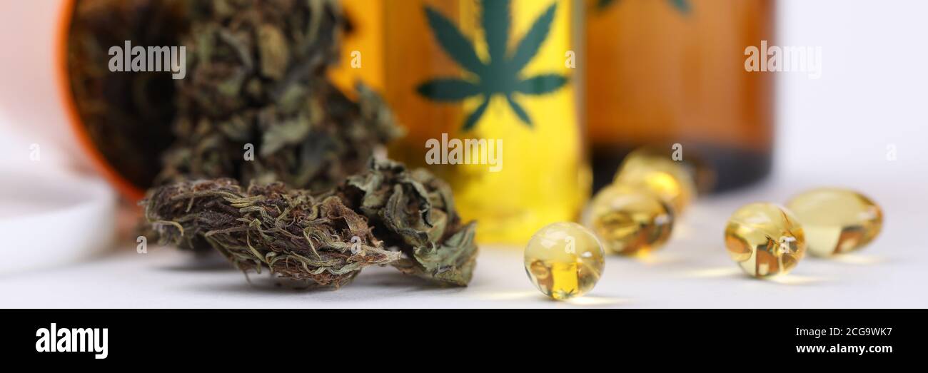 Sulla tavola marijuana in vaso e olio di canapa in capsule Foto Stock