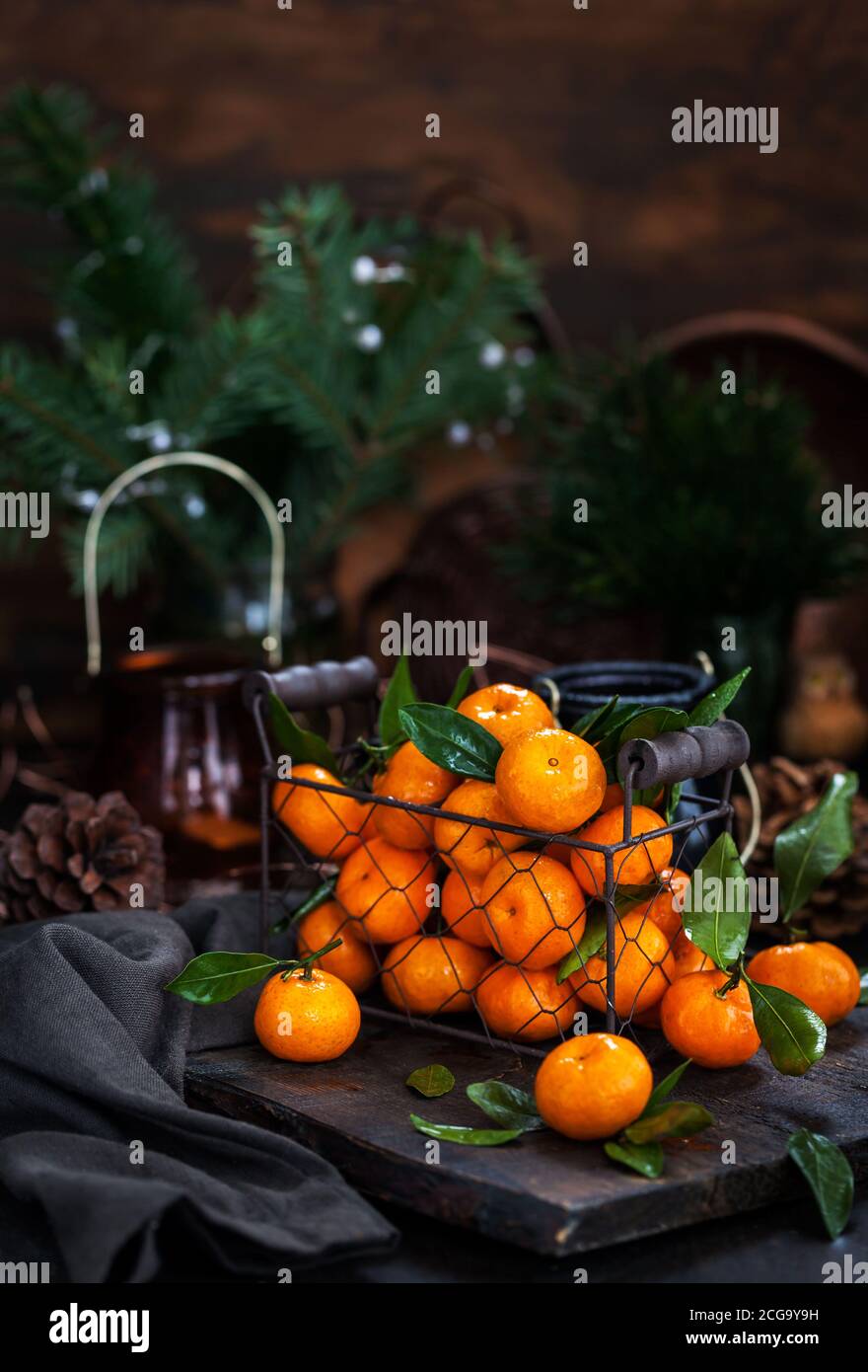 Tangerini freschi maturi con foglie su tavola di legno Foto Stock
