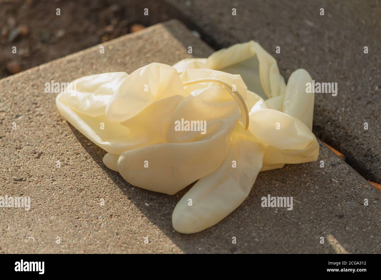Guanti in nitrile bianchi, stropicciati, usati, gettati su terra sporca. Foto Stock