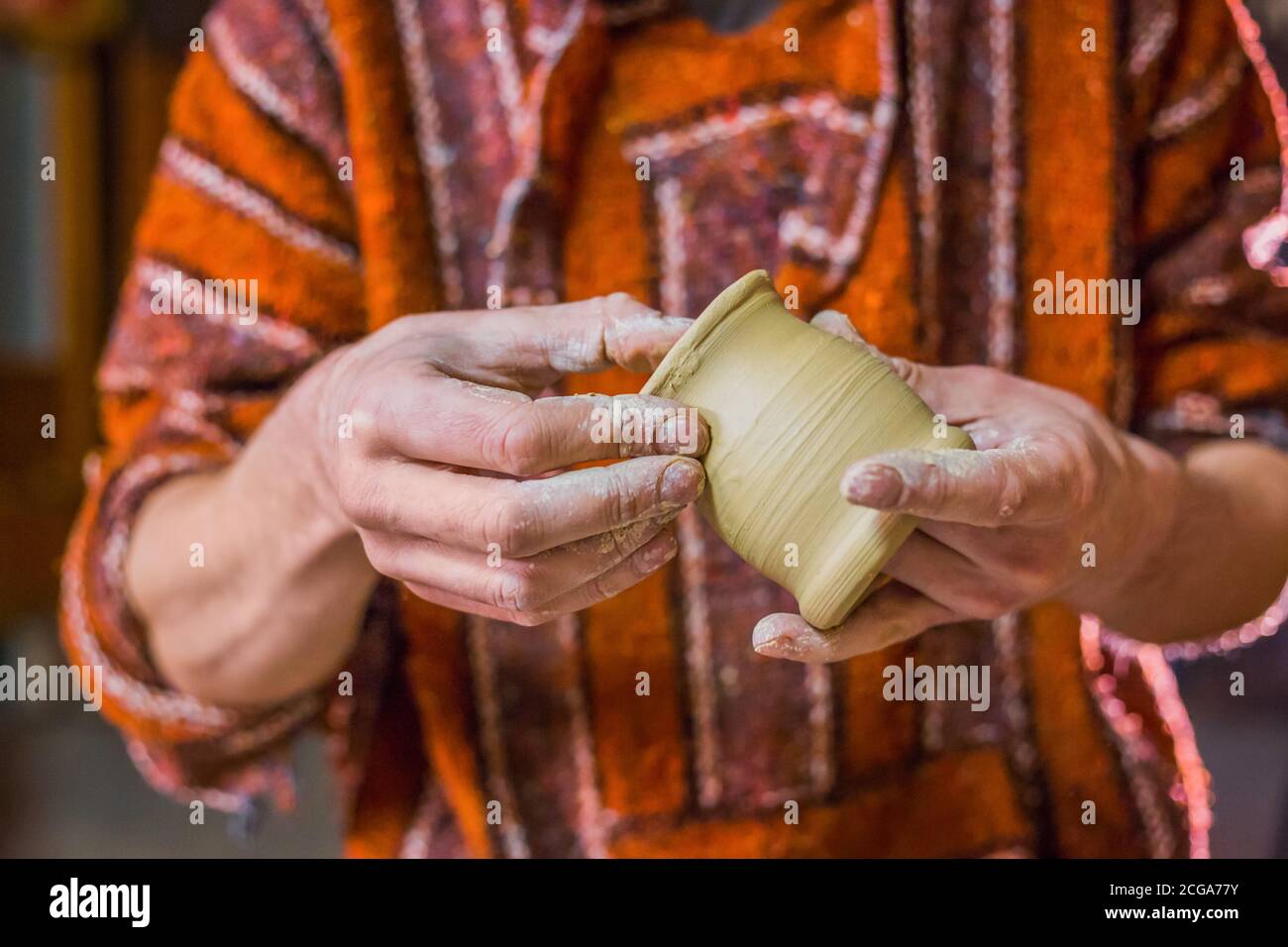 Maschio professionale potter esaminando vaso di terracotta nel laboratorio di ceramica, studio. Creazione, artwork e concetto di fatti a mano Foto Stock