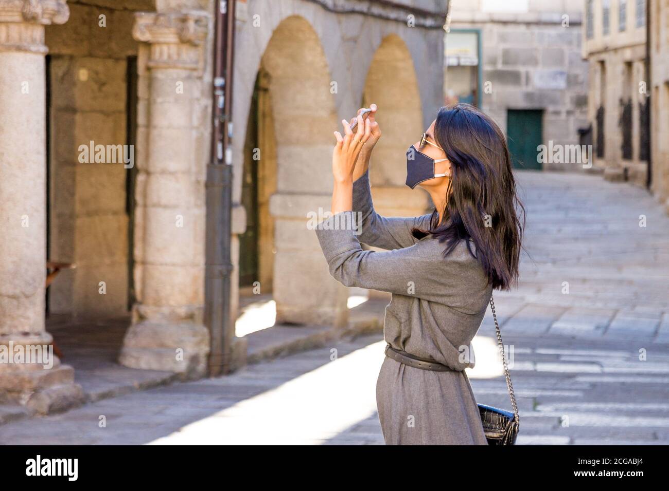 Ragazza che indossa una maschera riutilizzabile per scattare una foto mentre si viza una nuova città Foto Stock