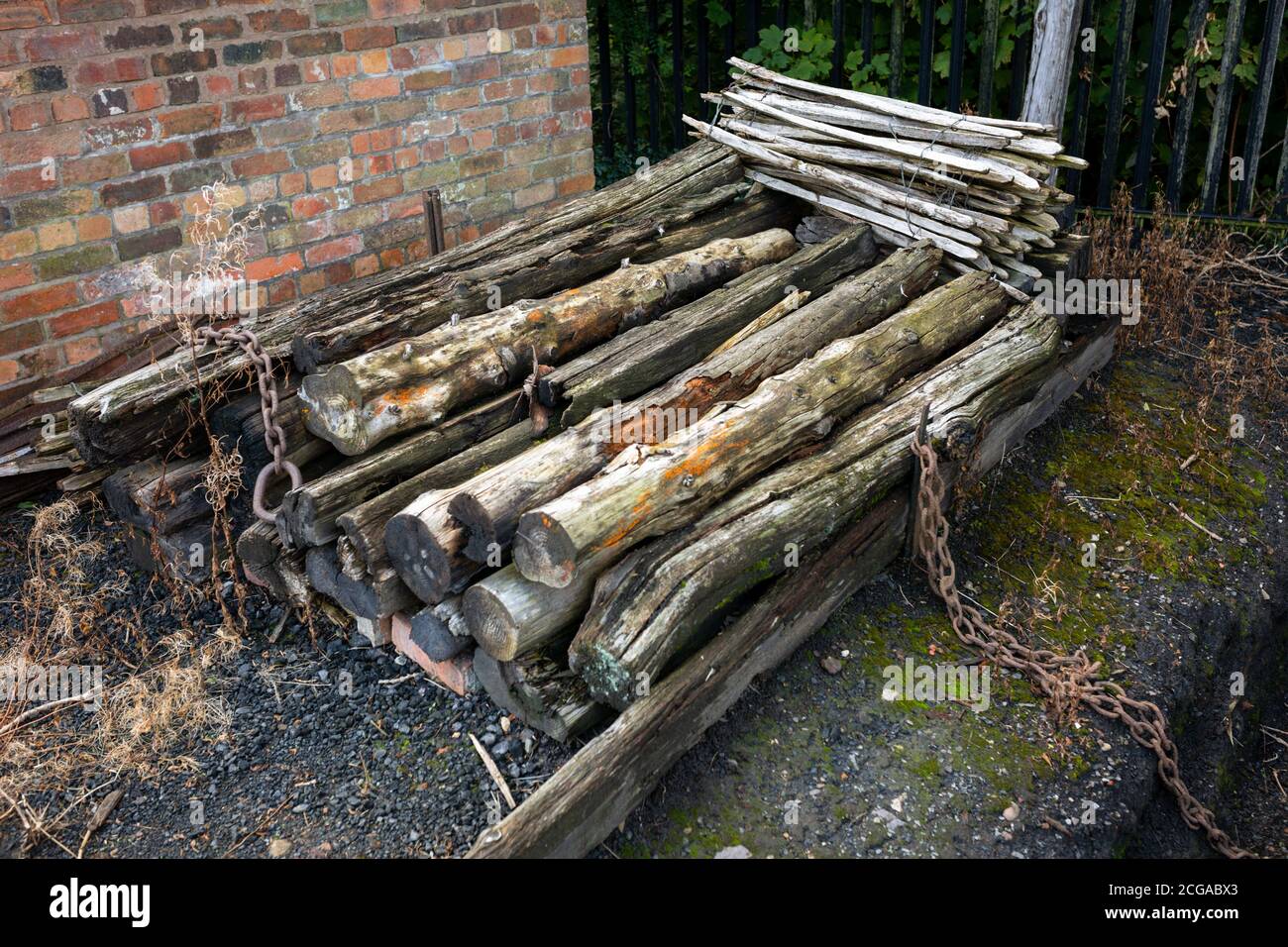 Vecchi pali di legno giacenti in un cantiere industriale Foto Stock