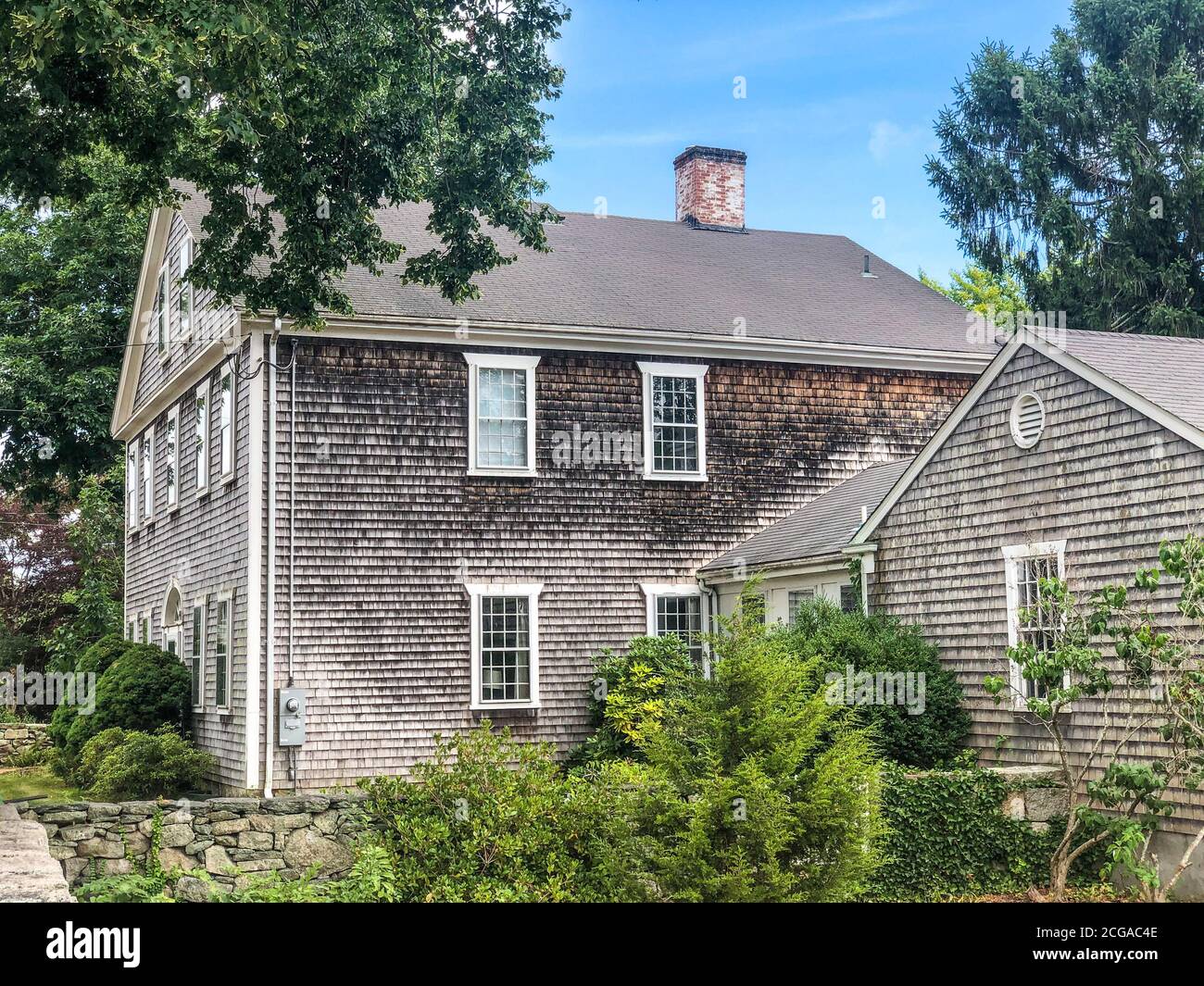 Una vecchia casa coloniale con legno intemperato scossa cedro in un villaggio del New England vicino all'oceano. Foto Stock