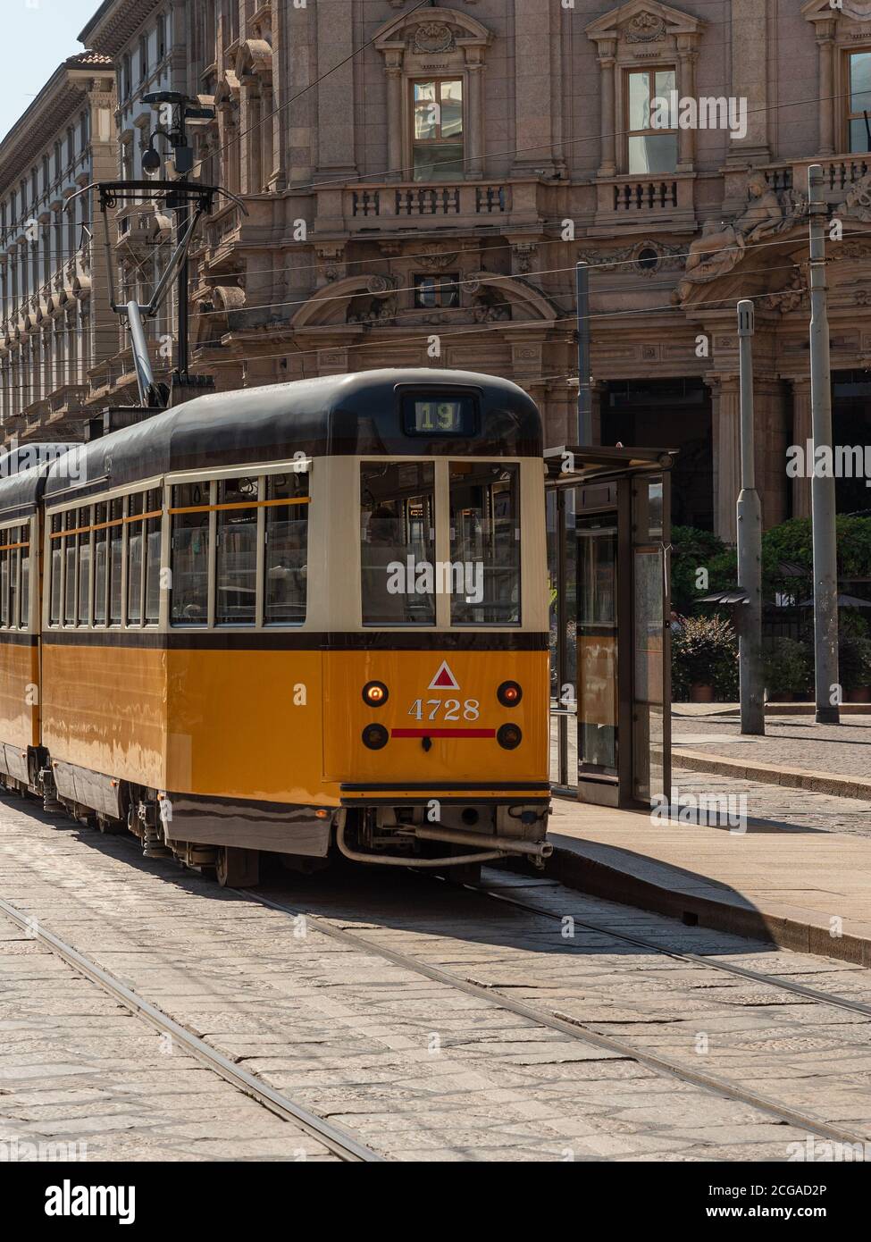 Un tram giallo passa attraverso le strade della città di Milano, uno storico trasporto pubblico italiano Foto Stock