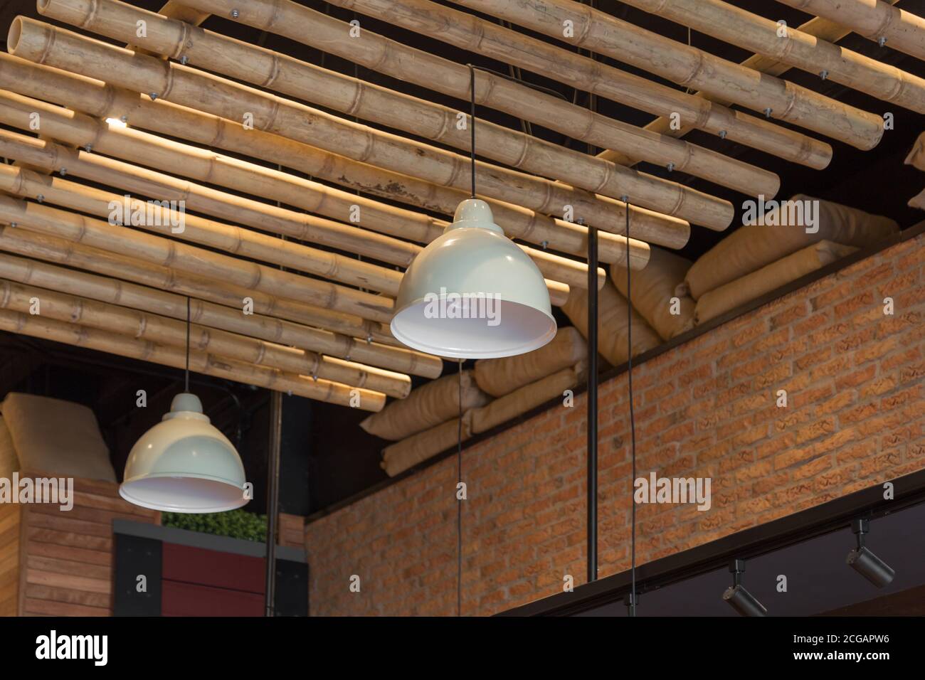 design del soffitto con travi in legno, moderne lampade bianche e mattoni parete Foto Stock