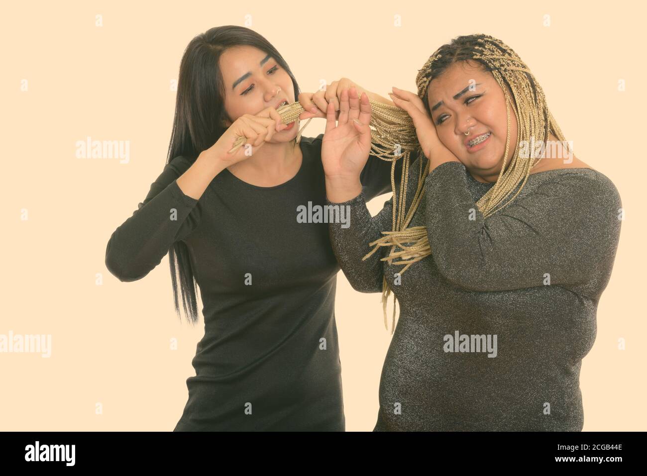 Giovani asiatici transgender donna mangiare e tirando i capelli di grasso donna asiatica Foto Stock