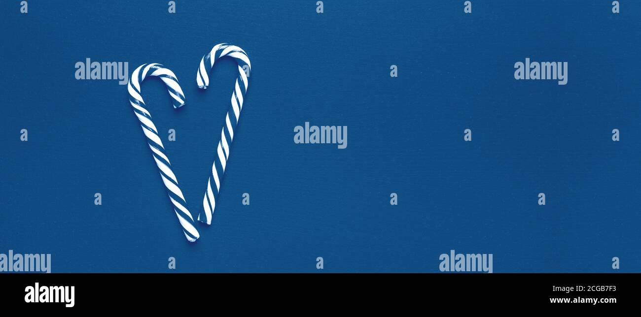 Composizione di Natale monocromatica di colore blu. Due canne caramelle a forma di cuore su sfondo di legno. Concetto di nuovo anno 2020 - immagine Foto Stock