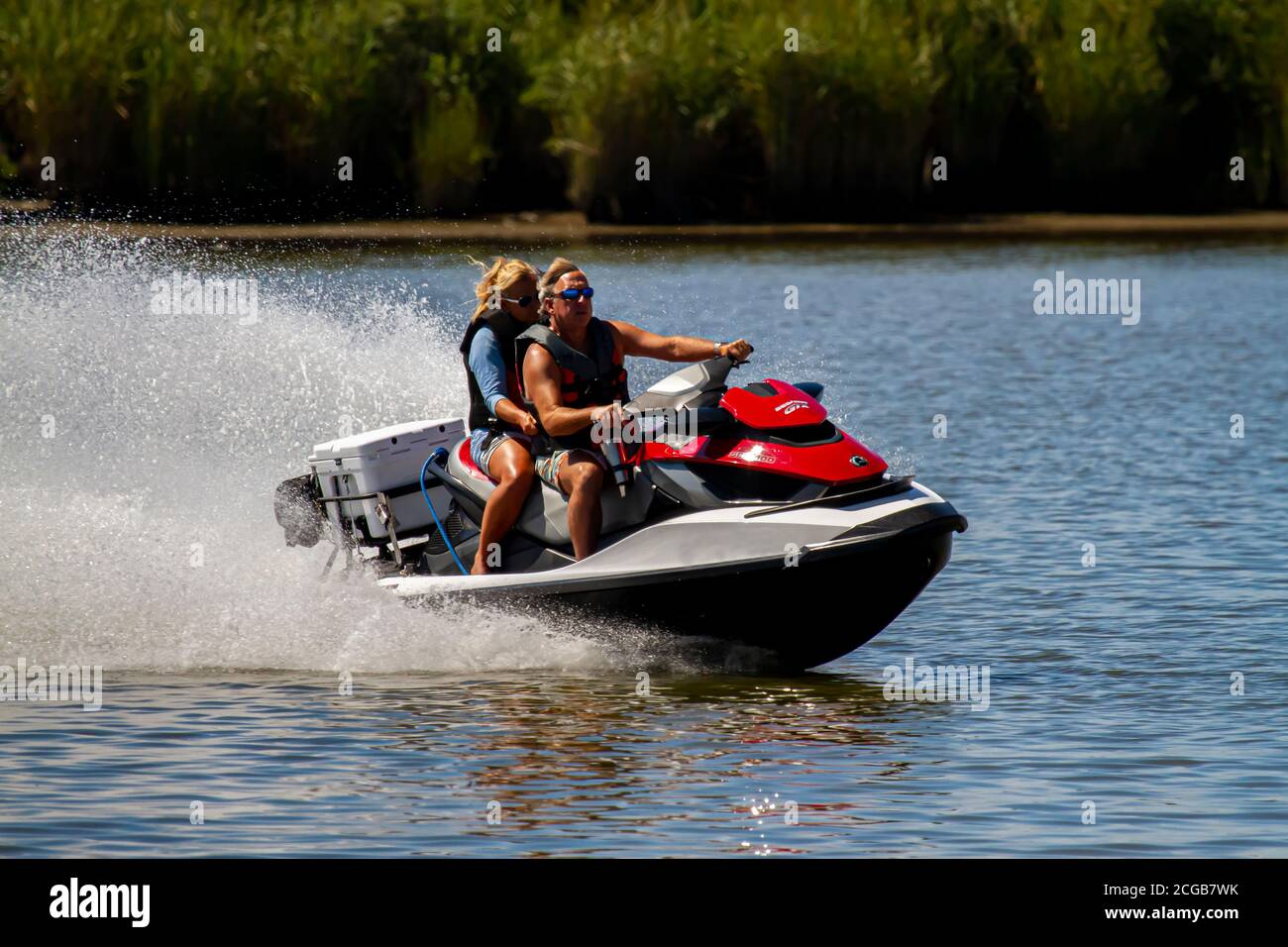 Eastern Neck Island, MD, USA 08/30/2020: Una coppia caucasica di mezza età che indossa giubbotti di vita sono su un Sea Doo GTX personal water craft. Si muovono davvero Foto Stock