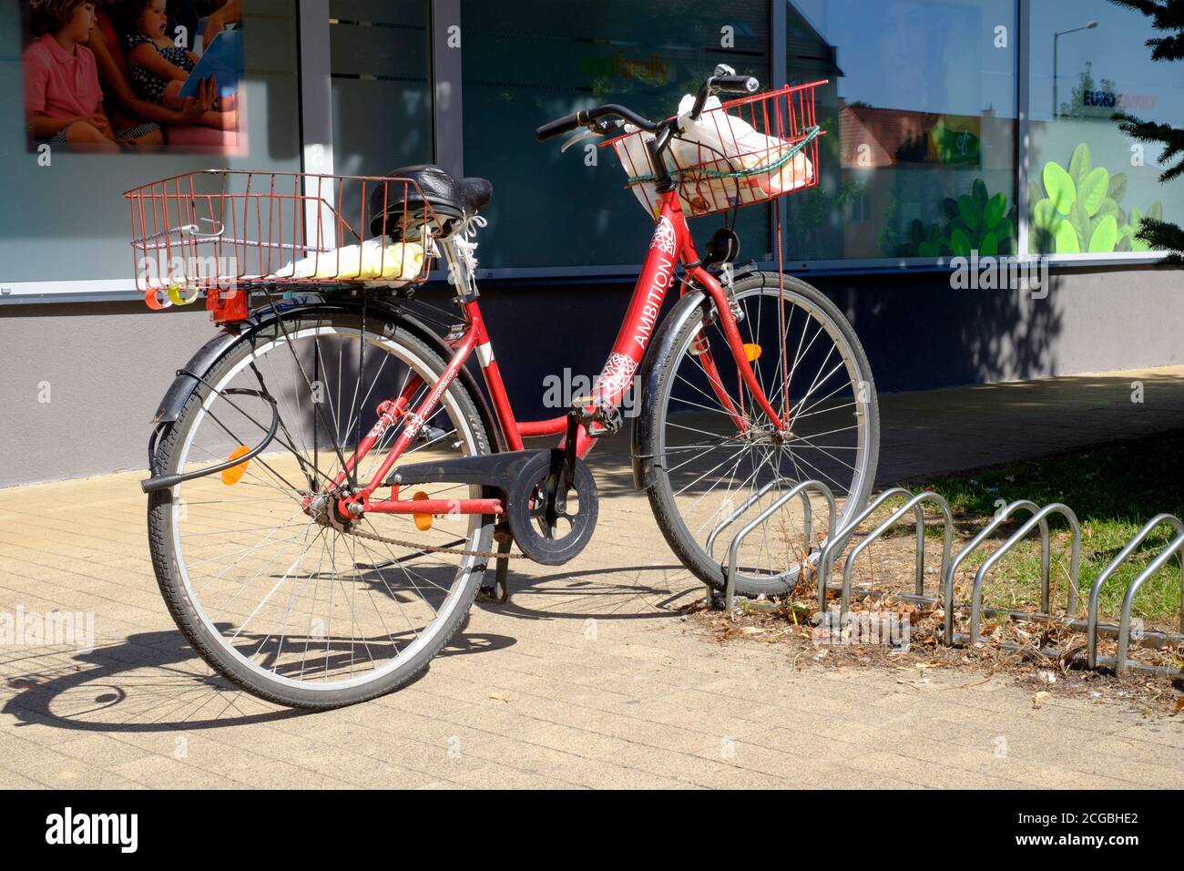 bicicletta con gli alimentari nel cestino anteriore lasciato incustodito con serratura a gettone flimsy nella tipica cittadina di mercato ungherese a basso crimine lenti zala contea ungheria Foto Stock