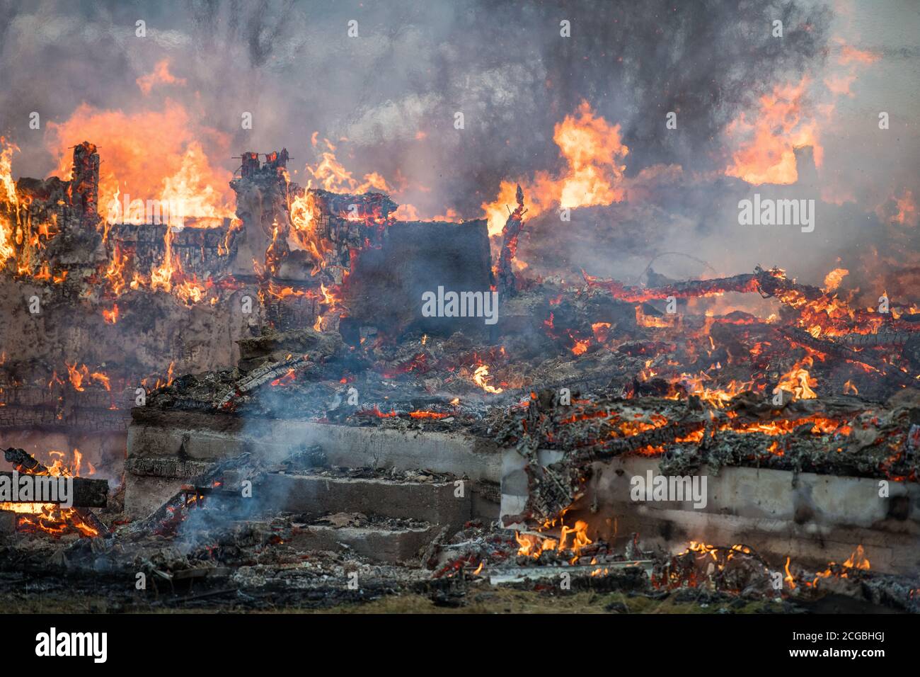 Rovina di case di legno con fiamme, bagliore e fumo, dopo bruciata Foto Stock